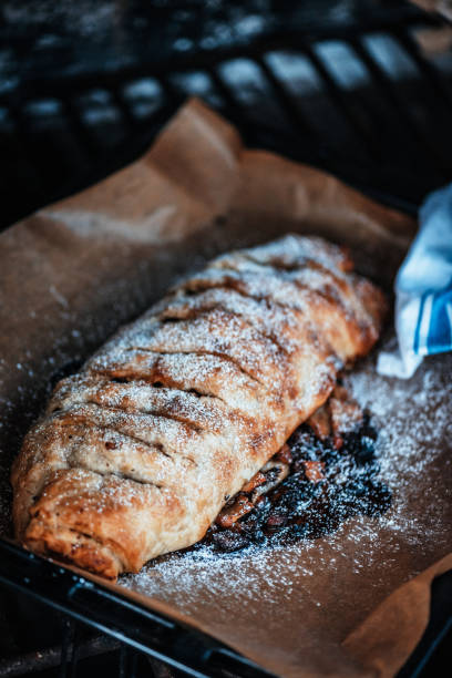 Homemade Apfelstrudel with Vanilla Sauce Homemade Apfelstrudel with Vanilla Sauce, puff pastry filled with caramelized almonds and green raisins – vegan, plant-based food apple strudel stock pictures, royalty-free photos & images