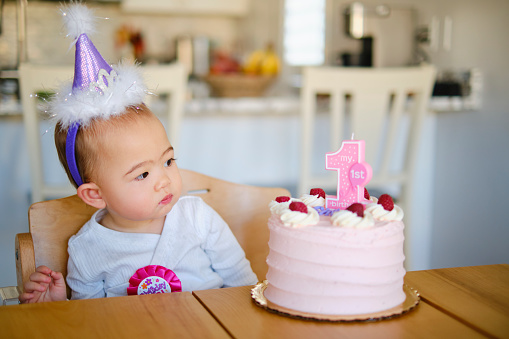 A Japanese American baby girl, celebrating her first birthday with a cake and decorations.