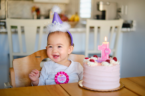 A Japanese American baby girl, celebrating her first birthday with a cake and decorations.