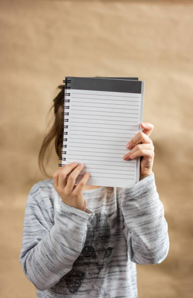 istock Child covering her face whit blank paper 1296561569