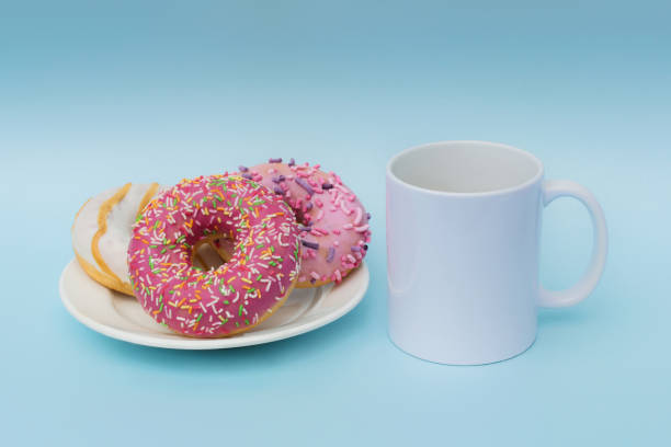 istock Absolutely white mug on a blue background. Nearby on a plate are three delicious, beautiful, seductive, high-calorie donuts. Unhealthy food. Breakfast concept. Romantic breakfast. Horizontal photo 1296563309