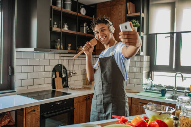 Young African American man is having fun in the kitchen and taking selfie