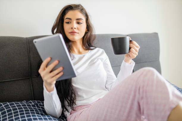istock Young woman drinking coffee and resting in bed 1296564855