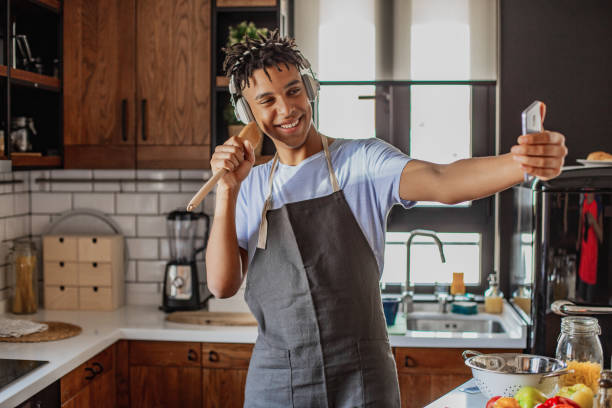istock Young African American man is having fun in the kitchen and taking selfie 1296565022