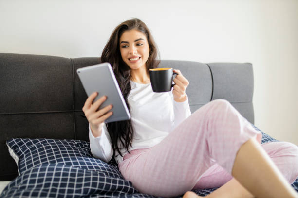 istock Young woman drinking coffee and resting in bed 1296566513