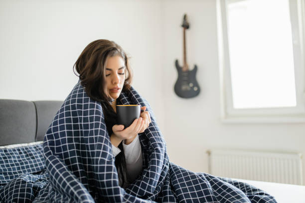 病気の女性は高熱でベッドに横たわっている。風邪と片頭痛 - 冷気 ストックフォトと画像