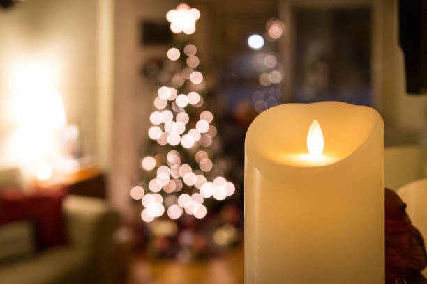 istock Close-up candle with blurry Christmas tree in background 1296569680