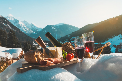 Traditional Italian food and drink in sunny winter day. Romantic alpine picnic in Dolomites with mountains background