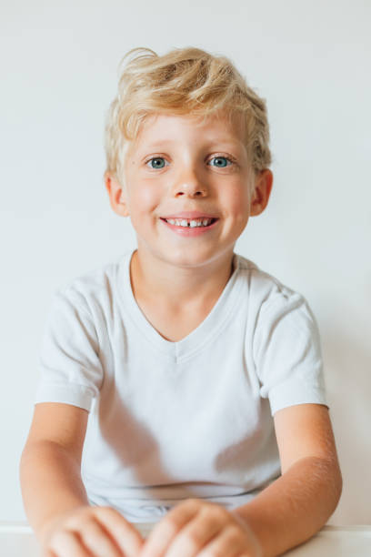 verticale de garçon blond de sourire - elementary age focus on foreground indoors studio shot photos et images de collection
