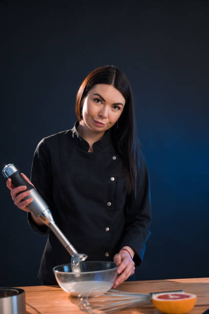 istock Lovely woman mixing flour with eggs while using whisk. She is cooking bakery. 1296575815