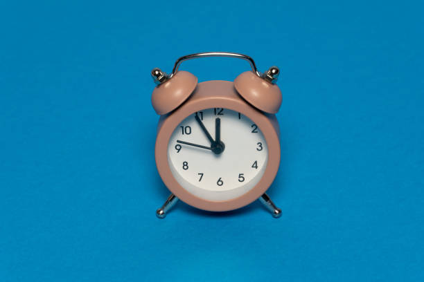 istock Brown alarm retro clock on blue background 1296581230
