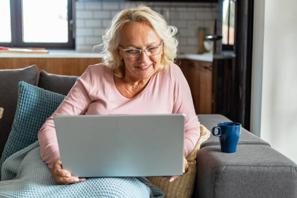 istock Senior woman relaxing at home and using laptop 1296585115