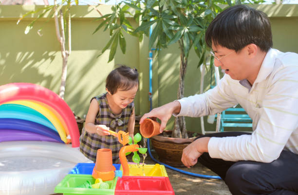 행복한 아시아아버지와 딸이 집에서 물 테이블을 가지고 노는 재미, 젖은 쏟아져 몬테사이 유치원 실습 활동, 미세 모터 기술 개발 - fine motor skills 뉴스 사진 이미지