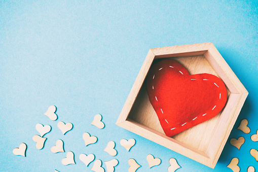 Top view of red textile heart in a wooden house decorated with small hearts on colorful background. Shape of heart. Home sweet home. Valentine's day concept.