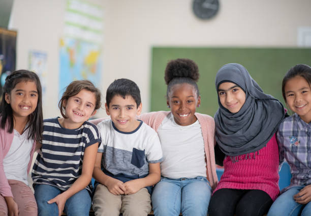 A super adorable multi ethnic group of elementary school children sitting close together for a photo.