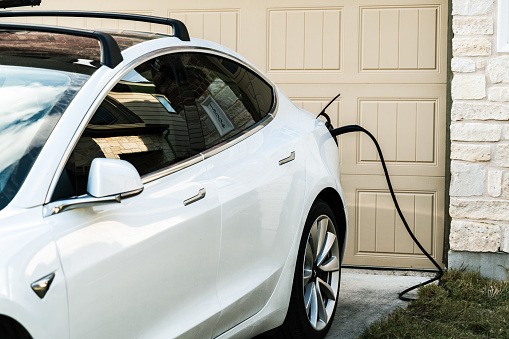 Austin , Texas , uSA - 2-1-2021: Tesla Model 3 charging at home in front of the house on the L2 at home charging that is provided with every Tesla vehicle