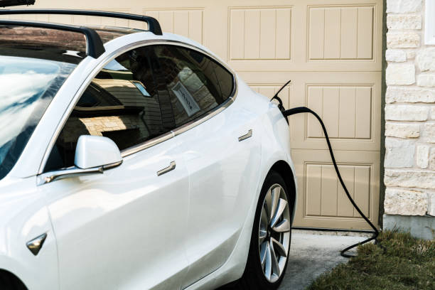 White Tesla Model 3 Charging at Home Austin , Texas , uSA - 2-1-2021: Tesla Model 3 charging at home in front of the house on the L2 at home charging that is provided with every Tesla vehicle ev charging stock pictures, royalty-free photos & images