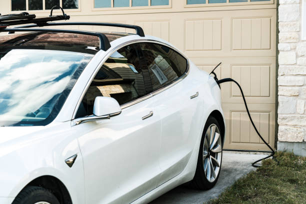 White Tesla Model 3 Charging at Home Austin , Texas , uSA - 2-1-2021: Tesla Model 3 charging at home in front of the house on the L2 at home charging that is provided with every Tesla vehicle tesla model 3 stock pictures, royalty-free photos & images