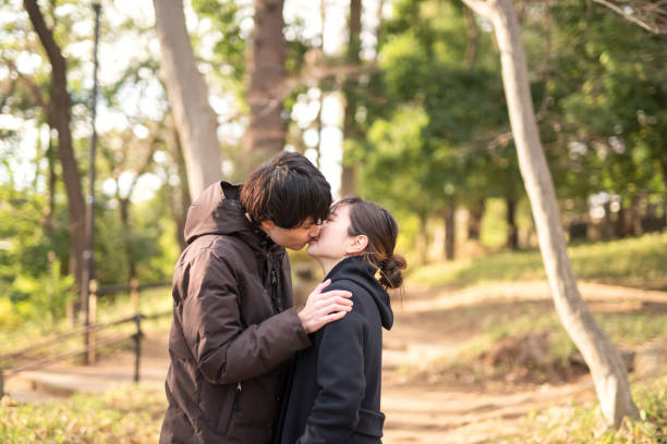 istock Young couple kissing in park 1296620374