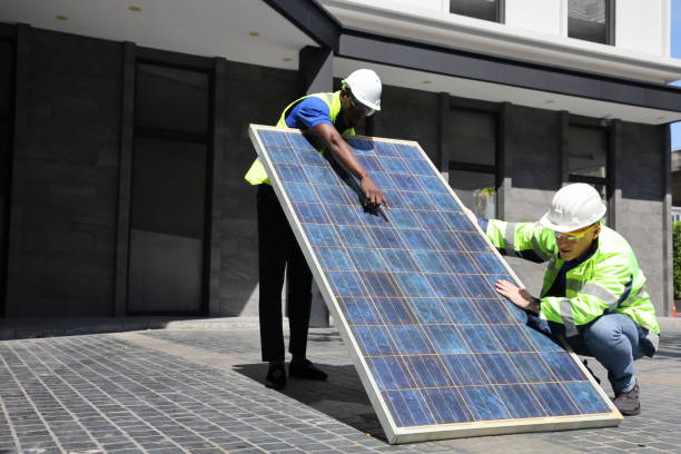 Caucasian and African American workers working on installing solar panel on the rooftop of the house for renewable energy and environmental friendly and sustainable development