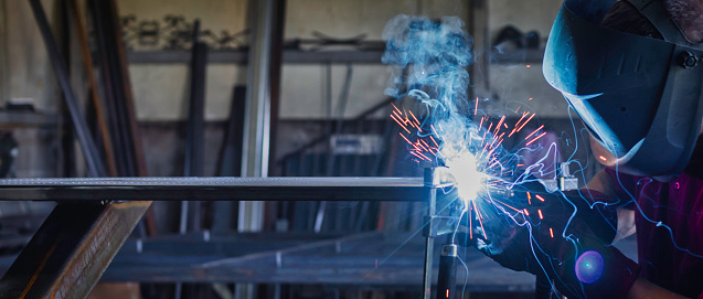 Industrial Welder With Torch in big hall welding metal profiles