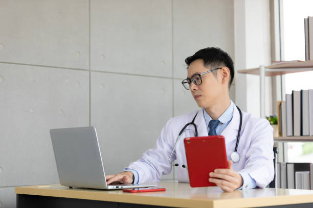istock asian doctor talking with patient and co-worker through online video chat with computer and holding tablet in hospital 1296623513
