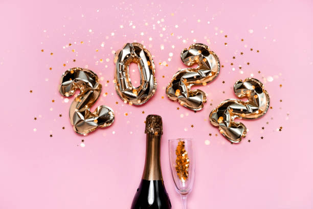 2021 golden foil balloons numbers, champagne, stars confetti, ribbons and bokeh. Top horizontal view copy space new year and holiday concept 2022 golden foil balloons with champagne bottle and confetti. Happy new year and festive concept. Top horizontal view copyspace. cham mask stock pictures, royalty-free photos & images