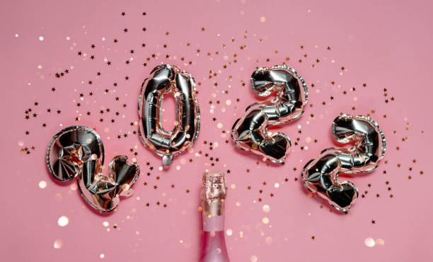 2022 golden foil balloons with champagne bottle and confetti. Happy new year and festive concept. Top horizontal view copyspace. 2022 golden foil balloons with champagne bottle and confetti. Happy new year and festive concept. Top horizontal view copyspace. cham mask stock pictures, royalty-free photos & images