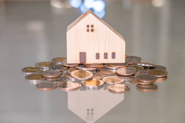 Selective focus at wooden house mock up that put on the top of growth money coins stack on the glass table with blurred background. Wealth and saving for home ownership and financial concept. enfoque selectivo en la maqueta de la casa de madera que poner en la parte superior de las monedas de dinero de crecimiento pila en la mesa de vidrio con fondo borroso. riqueza y ahorro para la propiedad de la vivienda y el concepto financiero.