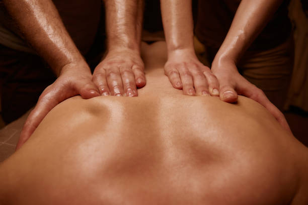 Back massage in the spa salon. Muscle recovery after exercise. Wellness. Back treatment. sports massage. The masseur does a back massage. Dim light in the spa. Masseur's hands stock photo