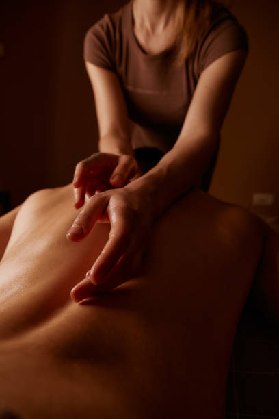 Back massage in the spa salon. Muscle recovery after exercise. Wellness. Back treatment. sports massage. The masseur does a back massage. Dim light in the spa. Masseur's hands stock photo
