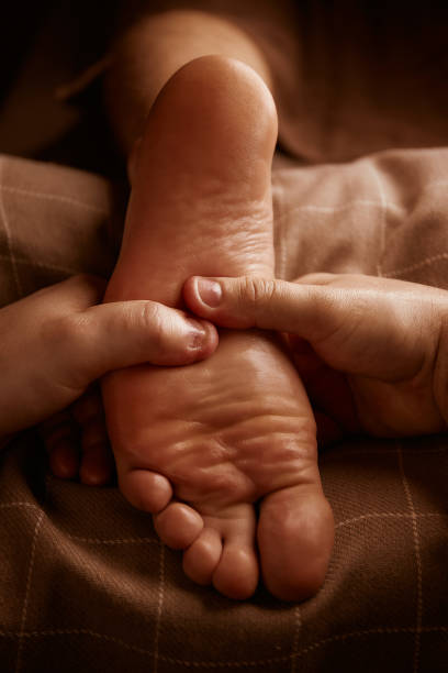 massage des pieds dans le salon spa. récupération du corps après l’exercice. bien-être. traitement des pieds. massage sportif. masseur faisant le massage de pied. traitement des pieds plats. lumières tamisées dans le spa - reflexology massaging recovery sport photos et images de collection