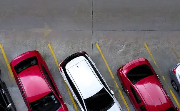 Photo of Top view of car parked at concrete car parking lot with yellow line of traffic sign on the street. Above view of car in a row at parking space. No available parking slot. Outside car parking area.