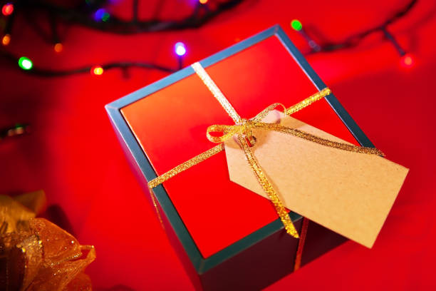 istock Gift box with a label for the text, red background with colorful lights from the back. 1296652810