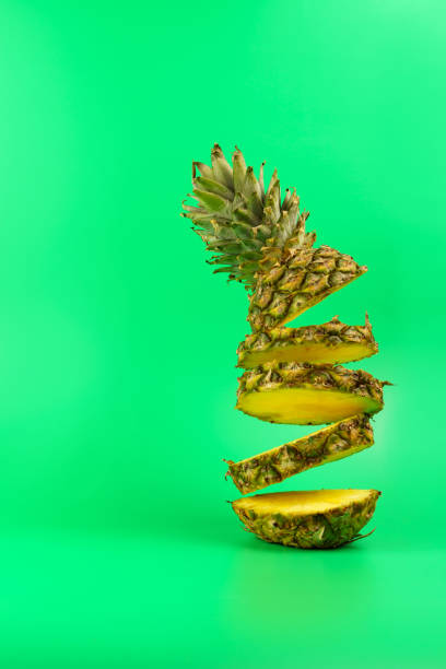 istock Pineapple sliced into rings, pineapple rings falling from top to bottom, on a green background. 1296653418