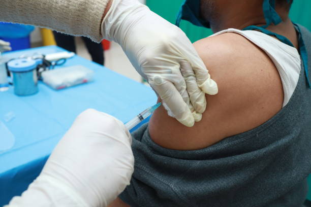 a close up photo of an intra muscular covid vaccine being given in arm of a patient by a doctor with gloved hand with selective focus on arm. a close up photo of an intra muscular covid vaccine being given in arm of a patient by a doctor with gloved hand with selective focus on arm. deltoid stock pictures, royalty-free photos & images
