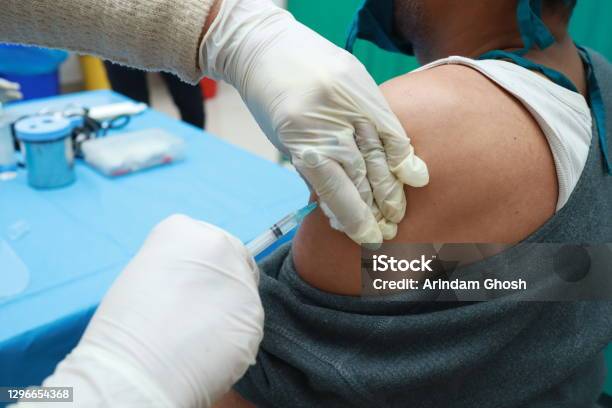 A Close Up Photo Of An Intra Muscular Covid Vaccine Being Given In Arm Of A Patient By A Doctor With Gloved Hand With Selective Focus On Arm Stock Photo - Download Image Now