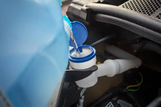 Photo of adding winter windscreen washer fluid in the car