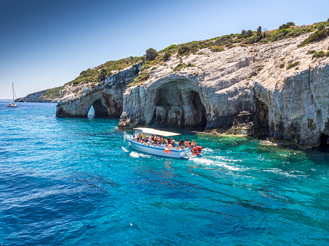 Beautiful lanscape of Ionian Sea from Keri, Zakinthos island, Greece. Vacation concept background. One tourboat with tourist heading for an exclusive beach.