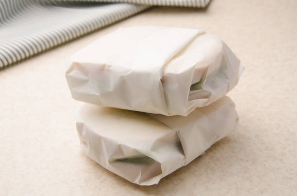 istock Two sandwiches wrapped in parchment paper on kitchen table 1296661480