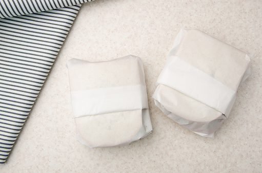 Flat lay view at two sandwiches wrapped in parchment paper on kitchen table