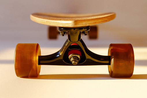 Closeup of wooden longboard wheel and suspension elements, soft focus. Front view