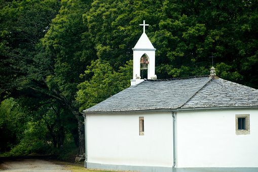Ancient small white church, forest in the background. Camino de Santiago, Galicia, Spain.