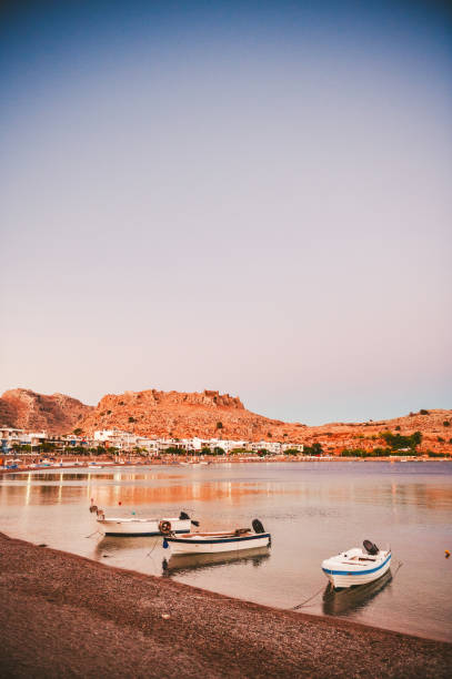 Evening light over Charaki bay, with boats parked and sun shining on the hill behind, Rhodes