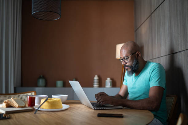 istock Mature man using laptop at home 1296671437