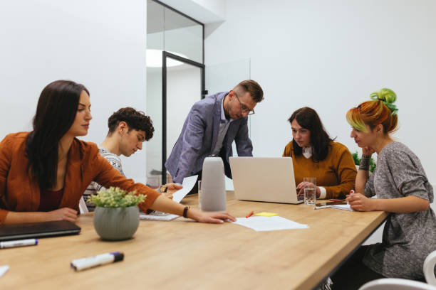 istock Male Mentor And Group Of Young Employees Analyzing Online Project 1296672159