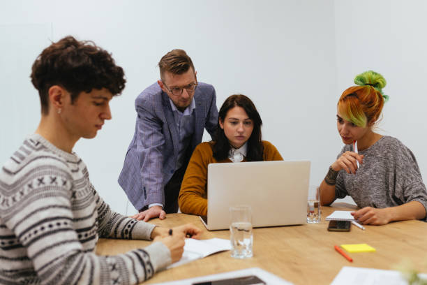 istock Male Mentor And Group Of Young Employees Analyzing Online Project 1296672180