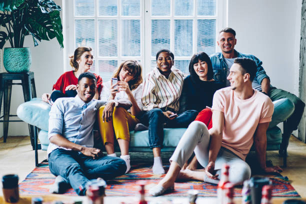 istock Happy multicultural people resting together at comfy home apartment sitting on cozy sofa, cheerful hipster guys laughing and relaxing in comfortable living room enjoying together leisure weekend 1296673284