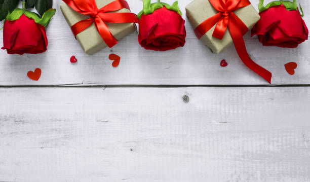 istock Valentine day background with red rose, hearts and gift boxes on white wood table with copyspace for text 1296673604