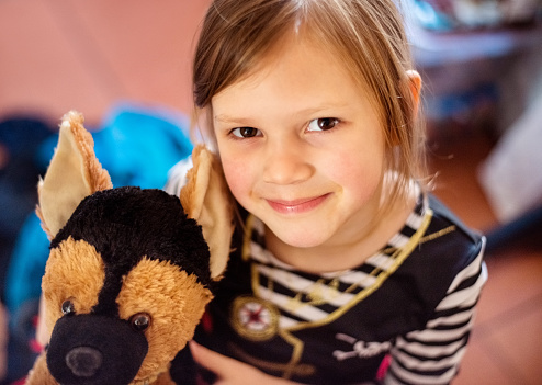 Closeup portrait of a beautiful little girl with her soft toy puppy looking at camera